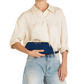A model wearing a cream-colored silk shirt and light-wash blue jeans holds a navy blue velvet clutch with a gold-tone kiss-lock closure.