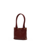A small leather tote bag in deep burgundy with gold-tone metal studs and double top handles, shown against a plain white background.