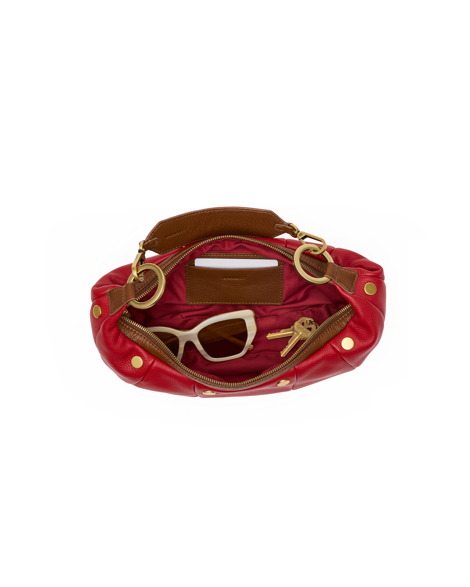 An open red leather shoulder bag with gold-tone hardware, showing a brown interior lining, sunglasses, and keys inside, set against a plain white background.