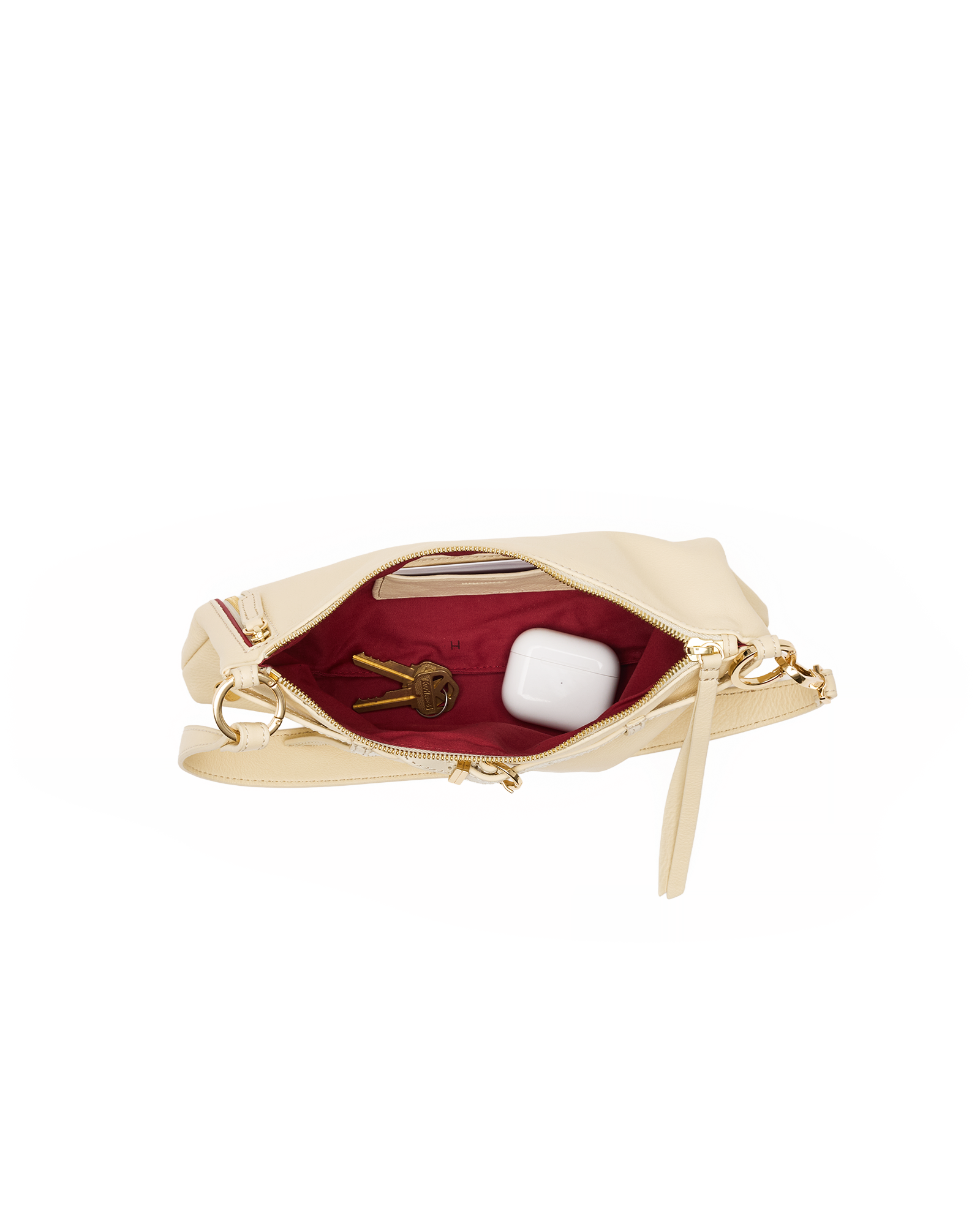 A cream-colored leather clutch bag shown open, revealing a deep burgundy red interior lining with gold-tone hardware, including a zipper pull and a ring clasp. The bag is photographed on a seamless white background.