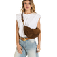 A woman wearing a brown suede crescent-shaped crossbody bag with gold-tone hardware, styled with a white sleeveless top and light blue jeans against a white background.