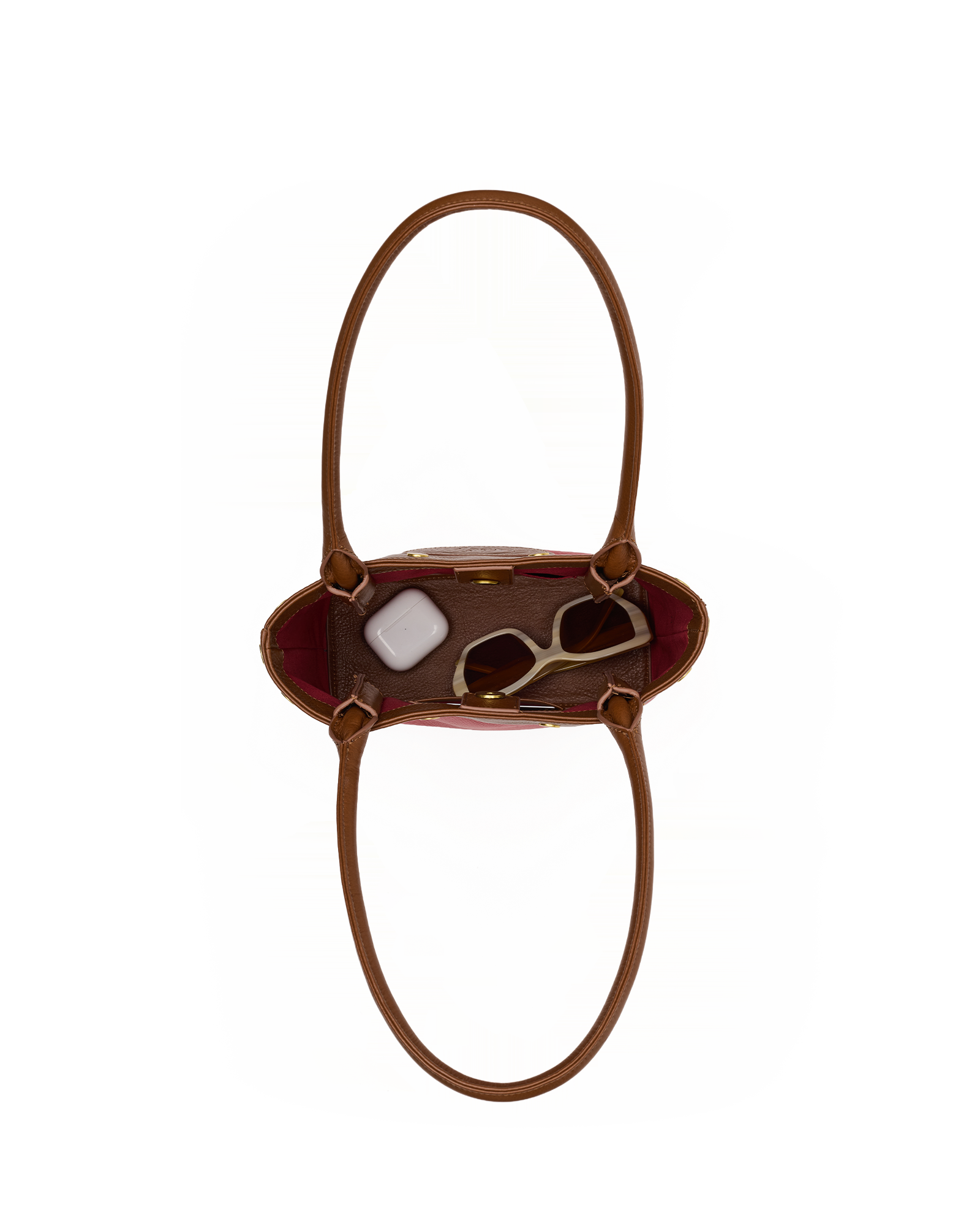 A brown leather handbag shown from a top-down view, containing sunglasses and a small white accessory, set against a plain white background.