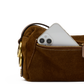 A close-up of a brown suede pouch or small bag with a gold-tone zipper, shown with a silver smartphone partially tucked into the pocket against a white background.