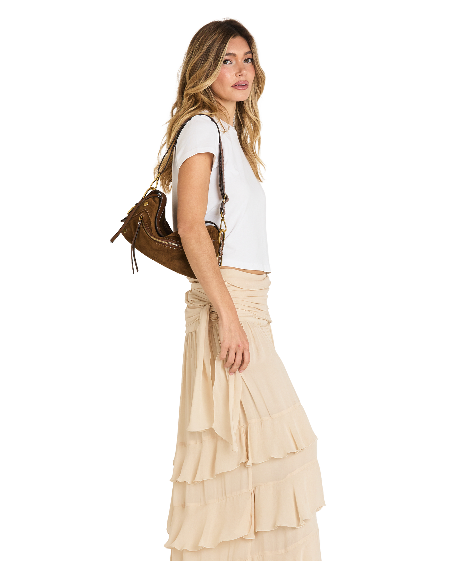 A woman in a white t-shirt and a beige ruffled tiered maxi skirt is shown from the side, carrying a brown leather shoulder bag against a solid white background.