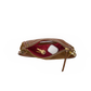 A brown leather clutch bag shown open, revealing a deep burgundy red interior lining with gold-tone hardware. Inside, a gold key and a white rectangular item are visible.