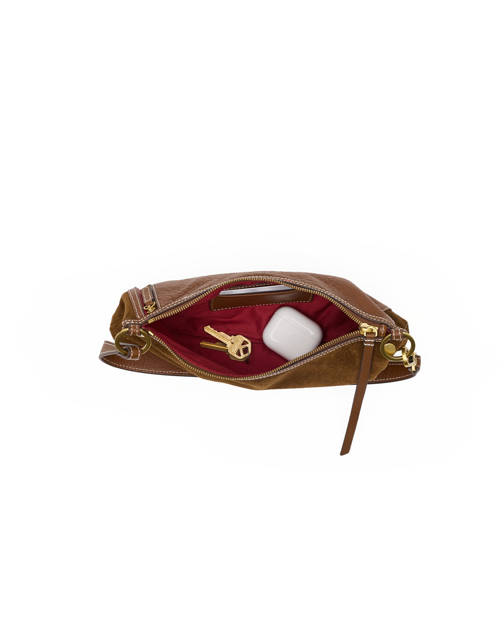 A brown leather clutch bag shown open, revealing a deep burgundy red interior lining with gold-tone hardware. Inside, a gold key and a white rectangular item are visible.