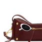 A burgundy leather shoulder bag with gold-tone hardware and a white-framed sunglasses accessory resting on top, shown against a solid white background.