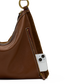 A brown leather shoulder bag with a gold-tone ring detail and a side zip pocket, shown with a white smartphone inserted into the pocket against a white background.