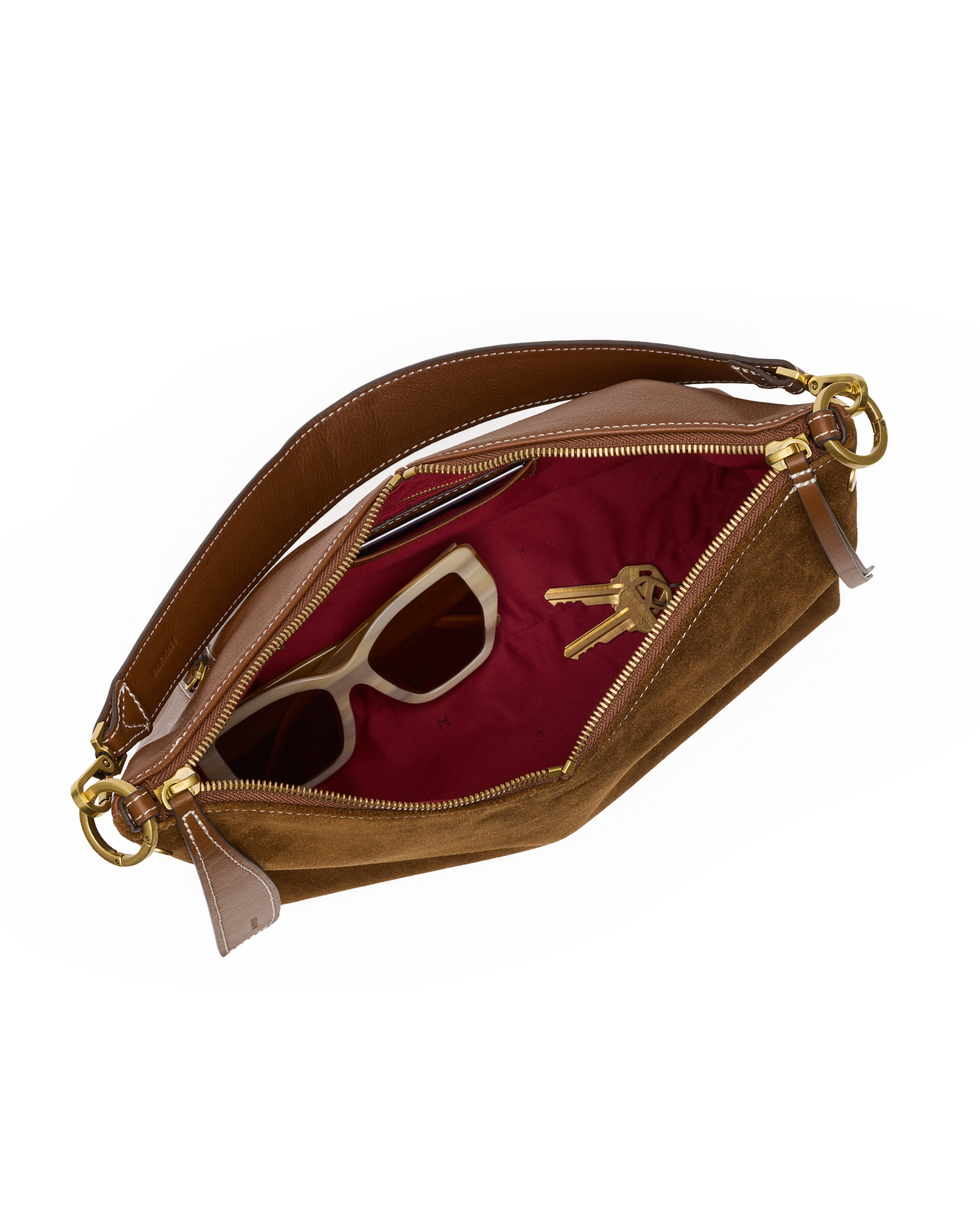 A brown suede and leather clutch bag shown open, revealing a burgundy red interior lining with a pair of sunglasses and keys inside, set against a plain white background.