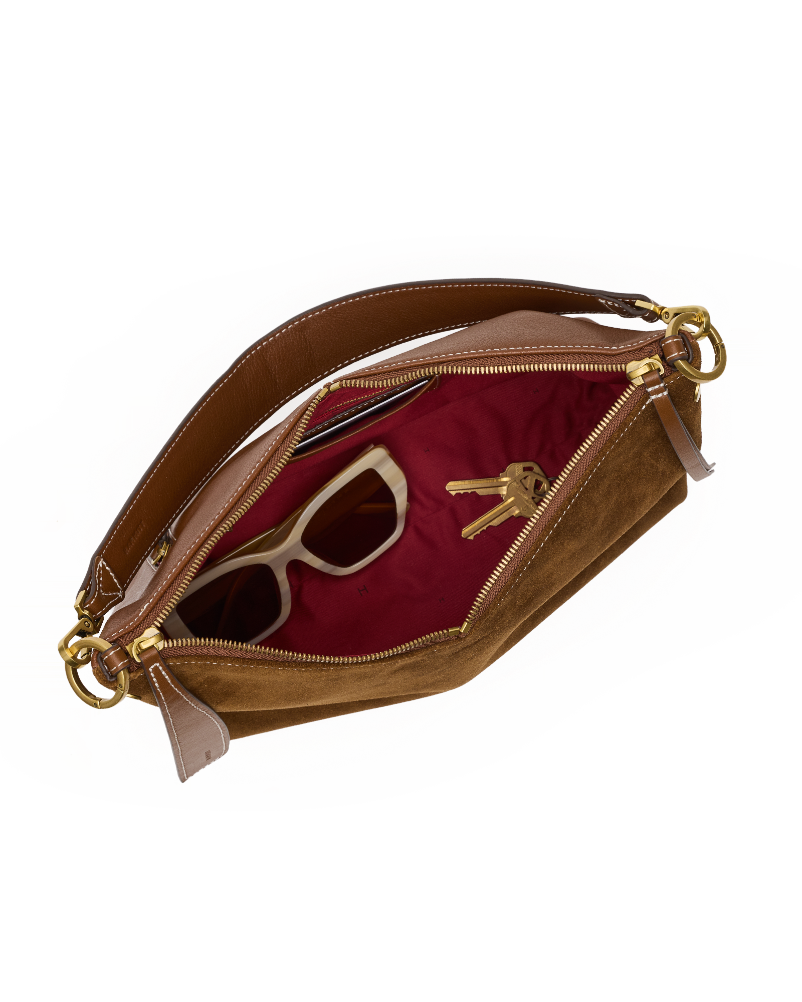 A brown suede and leather clutch bag shown open, revealing a burgundy red interior lining with a pair of sunglasses and keys inside, set against a plain white background.