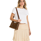 A woman modeling a brown suede crossbody bag with decorative gold-tone buttons, styled with a white crop top and a beige pleated skirt against a plain white background.