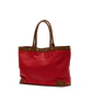 A red tote bag with brown leather handles and trim, accented by gold-tone metal studs, shown against a plain white background.