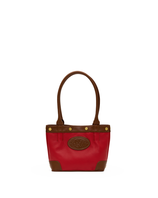A red leather handbag with brown leather trim, double top handles, and a circular embossed logo patch on the front, set against a plain white background.