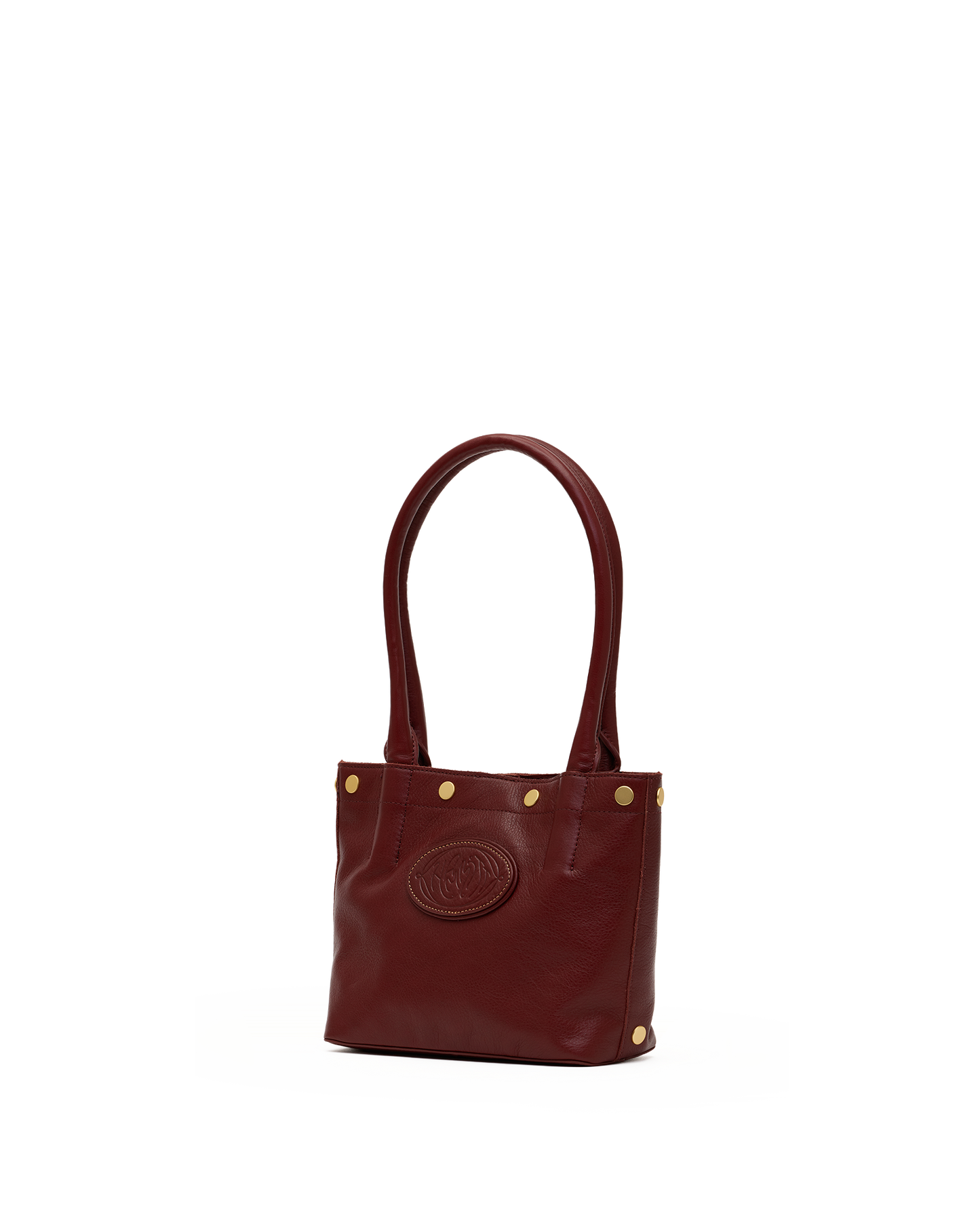 A small leather tote bag in deep burgundy with gold-tone hardware, featuring a circular embossed logo on the front and dual top handles, set against a plain white background.