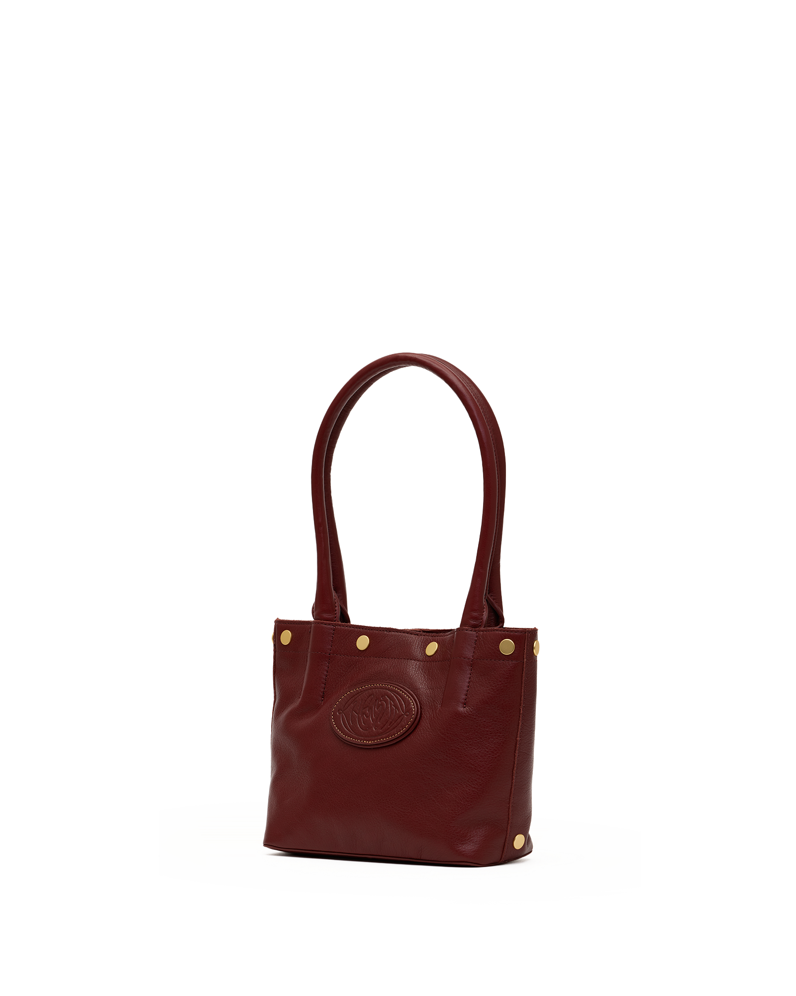 A small leather tote bag in deep burgundy with gold-tone hardware, featuring a circular embossed logo on the front and dual top handles, set against a plain white background.