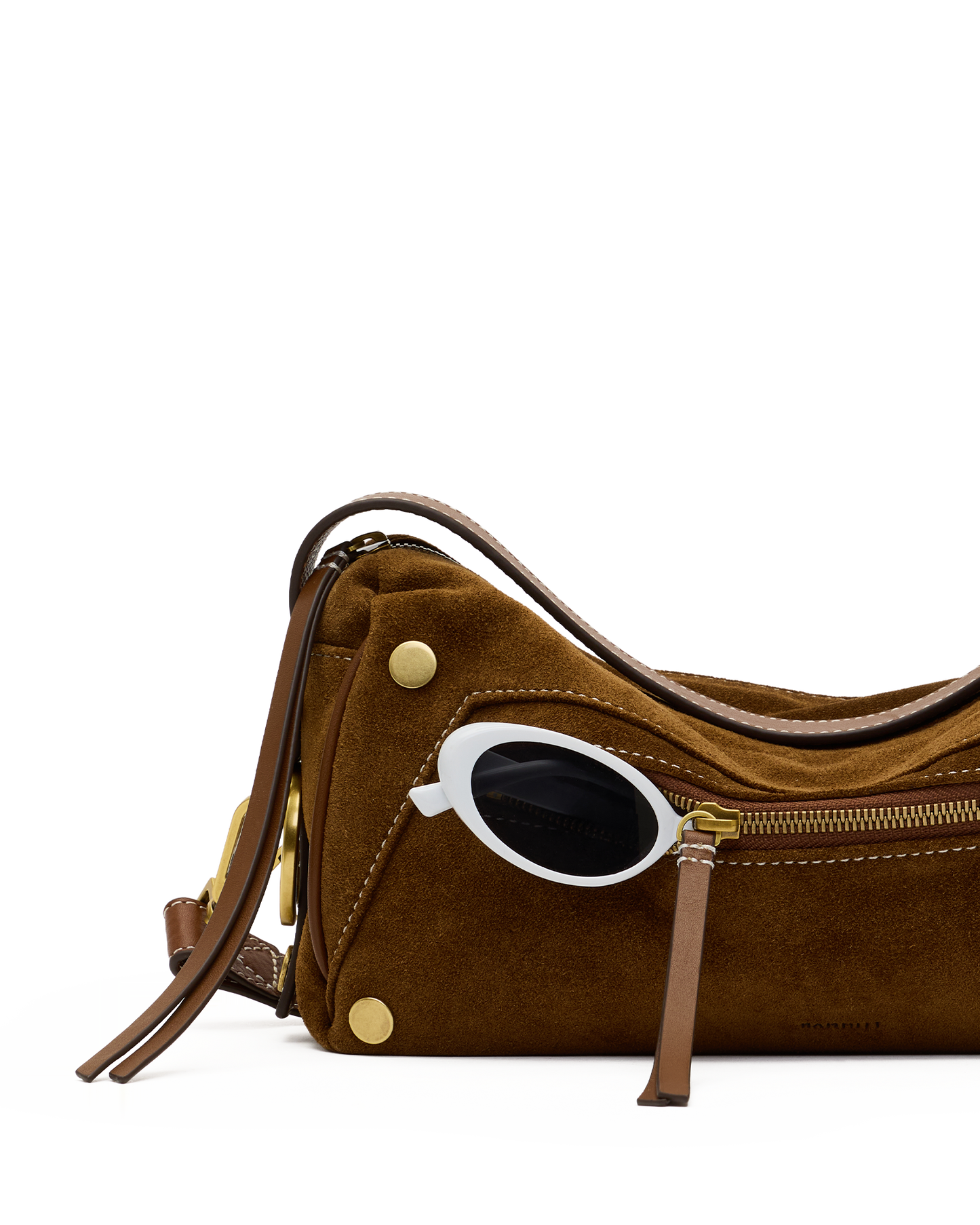 A brown suede shoulder bag with gold-tone hardware and a white oval frame sunglasses accessory tucked into the side zipper, photographed on a clean white background.