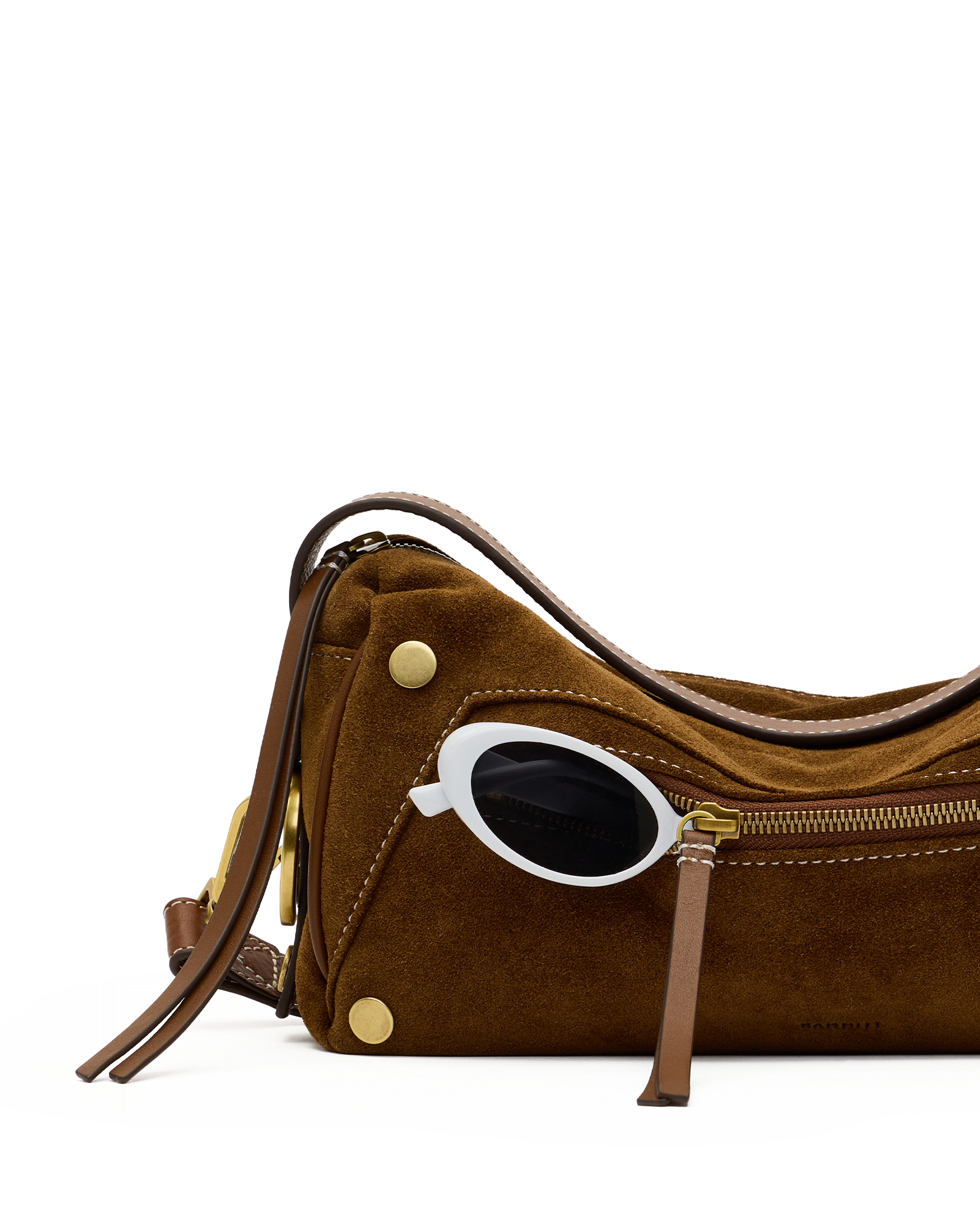 A brown suede shoulder bag with gold-tone hardware and a white oval frame sunglasses accessory tucked into the side zipper, photographed on a clean white background.