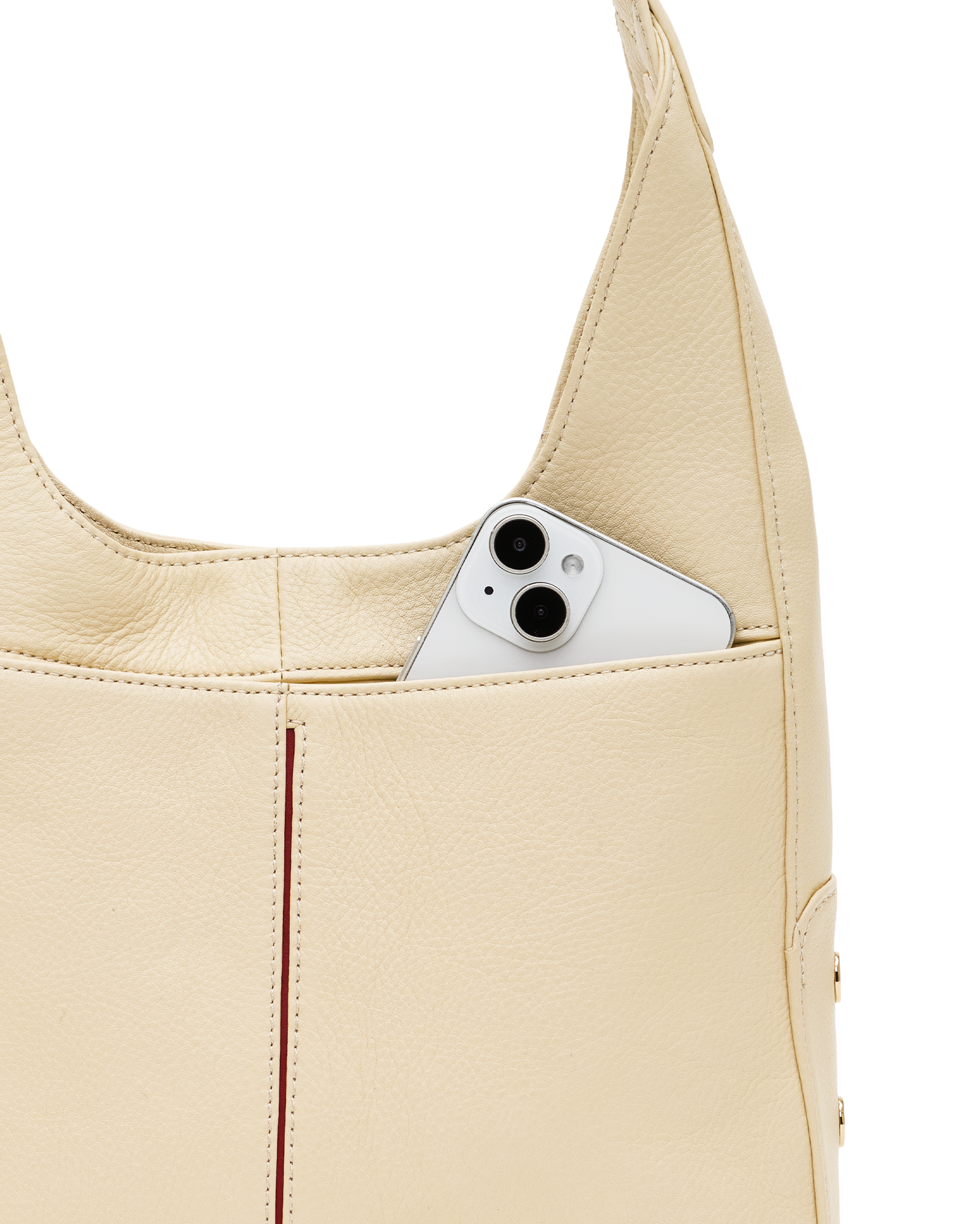 Close-up of a cream-colored pebbled leather shoulder bag with a silver smartphone tucked into its side pocket, set against a solid white background.