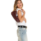 A woman posing in a white sleeveless top, light wash jeans, and a black belt, carrying a dark brown leather shoulder bag with gold-tone hardware against a plain white background.