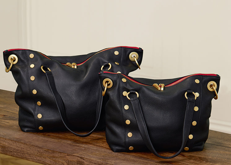 Two Daniels in Black Brushed Gold red Zip in both Lrg and Med on table.