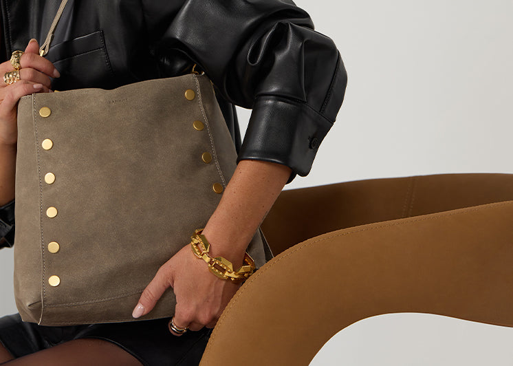 Model in black leather jacket holding Bryant LRg in Pewter bruhed gold over shoulder.