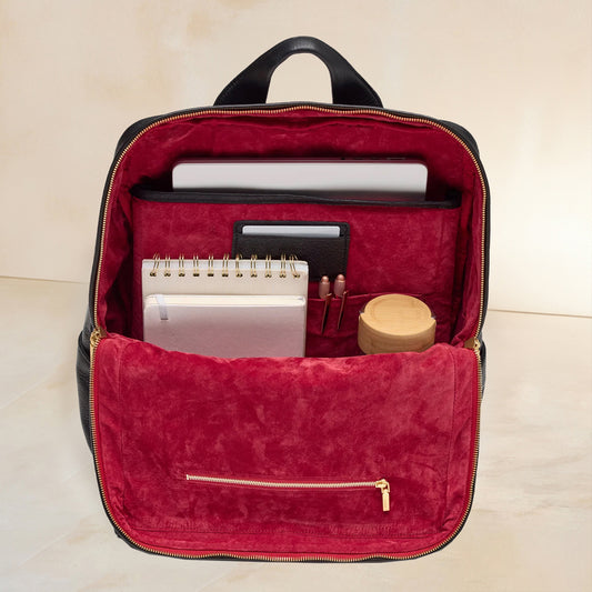 Interior shot of Montana XL backpack showing laptop, notbook, pens and water bottle inside of red intrior. 